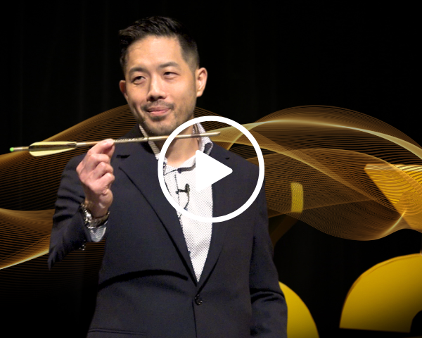 Dr Wiley Chung delivering his 5 à 7 talk while holding an arrow. A YouTube play button is overlaid with a link to the video.